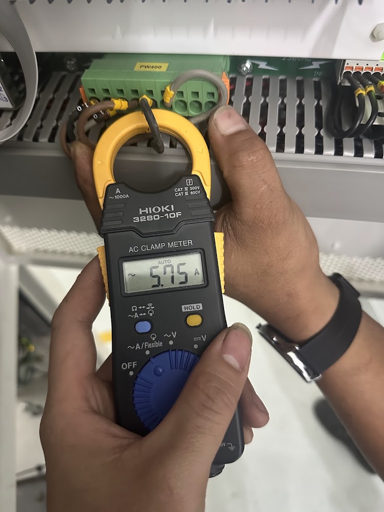 Kỹ sư đo dòng điện bằng ampe kìm khi sửa bộ điều khiển tủ thử nghiệm